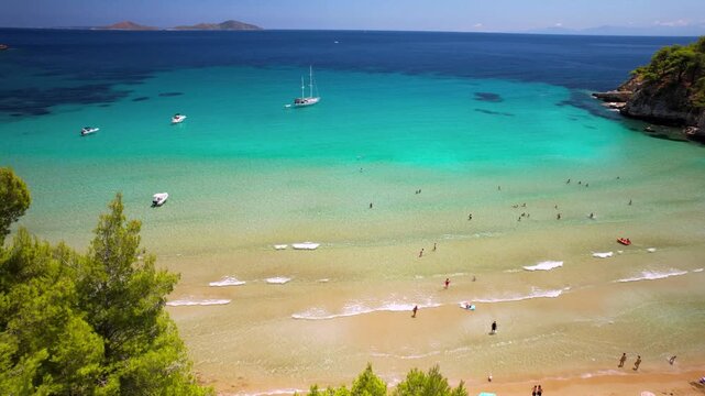Chrisi Milia Alonissos 4k drone reveal of golden sand beach and people swimming. Aerial crane shot of turquoise shallow water and waves in Greece. Tropical summer vacation b-roll