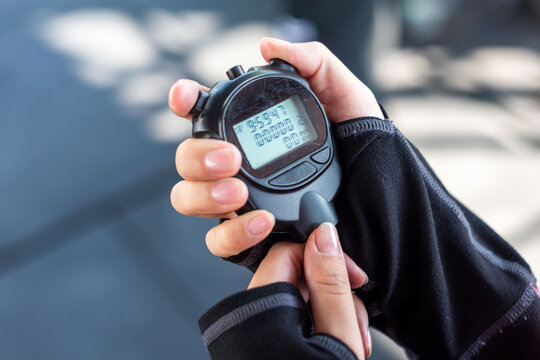 Hand holding digital stopwatch outdoors