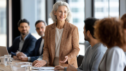 Fototapeta premium Defocused professional unrecognizable female executive presenting to a diverse team during a corporate strategy meeting in a modern office boardroom, leadership concept, with copy space