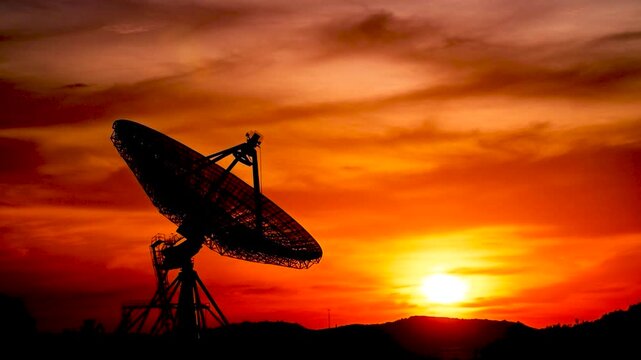 Satellite dish silhouette against a vibrant orange sunset sky. generated with AI
