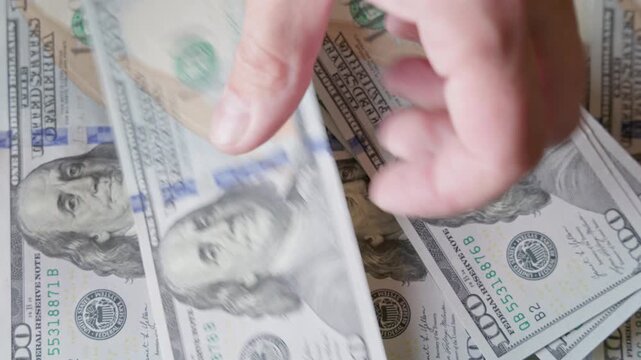 Adult person manipulates stack of paper currency indoors. Scene captures transactional mood with a focus on financial activity.