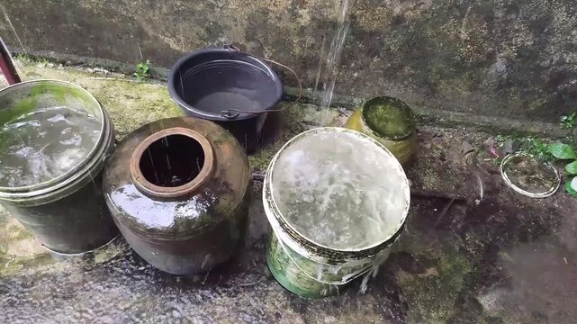 Water being poured into ceramic pots and buckets outdoors