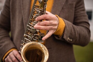 Obraz premium Close-up of hands playing an alto saxophone outdoors