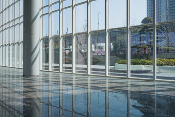 Naklejka premium Modern office building interior with glass curtain wall and reflective marble floor