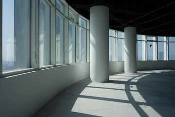 Obraz premium Curved floor-to-ceiling windows in a modern empty office space with concrete floors and white columns