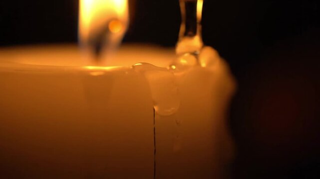Close-up of a melting candle with a warm glow on a dark background.