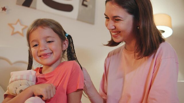 Mother and daughter share a joyful moment at home while playing and smiling together during the evening