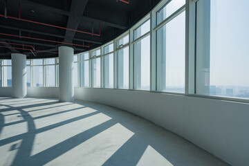 Obraz premium Modern empty office space with curved floor-to-ceiling windows and industrial ceiling details