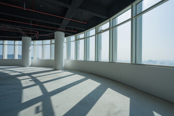 Obraz premium Unfinished modern office interior with abundant natural light through large windows and structural columns