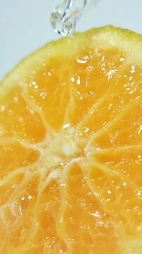 Dropping clear liquid onto a fresh orange slice. Liquid absorbs into citrus fruit fibers, scientific or cosmetic concept, vitamin C and freshness theme.