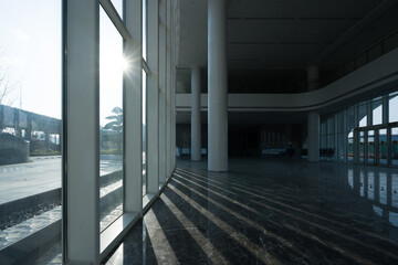 Obraz premium Sunlight streams through glass curtain wall into modern architectural lobby interior