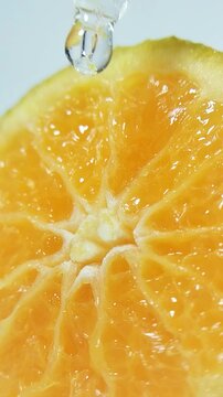 Water flowing from a pipette tip through fresh orange fruit fibers. Close-up macro shot, hydration and freshness concept, citrus slice with liquid droplets.