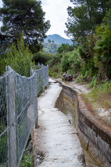 Fototapeta premium Scenic view of surrounding mountains and picturesque village from a hiking trail along an old irrigation ditch in Frigiliana, Spain.