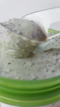 Scooping baby porridge or mung bean porridge from a green bowl. Close up view, creamy texture, healthy food for children, isolated on white background.