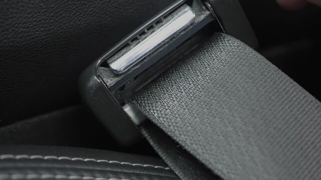 Driver ensuring seatbelt clicks properly in place. Person pressing metal latch until click confirms safety. Individual carefully securing seatbelt for safety before journey begins