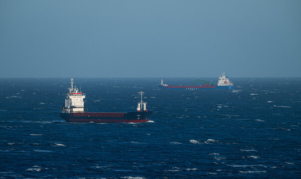 Lindesnes, Norway - June 19 2024: Cargo ships navigating rough open sea under clear daylight.