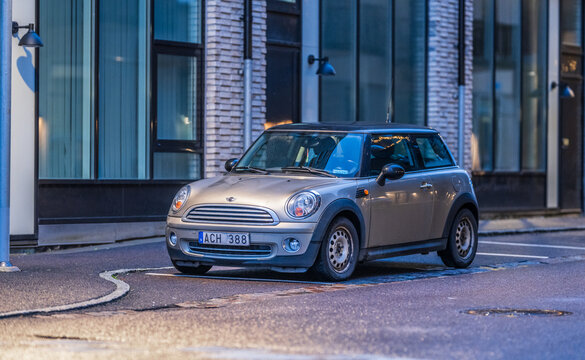 Gothenburg, Sweden - november 30 2025: 2007 Mini Cooper parked beside modern brick building at night.