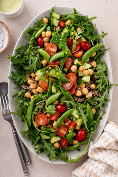 Fresh vegetables and quinoa salad with chickpeas, arugula and fresh peas with avocado ranch dressing