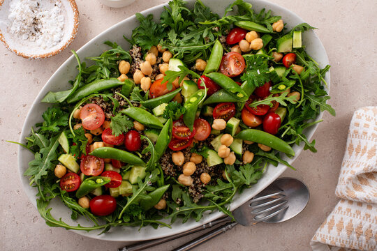 Fresh vegetables and quinoa salad with chickpeas, arugula and fresh peas with avocado ranch dressing