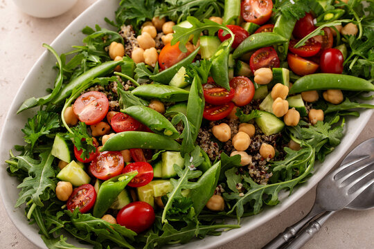 Fresh vegetables and quinoa salad with chickpeas, arugula and fresh peas with avocado ranch dressing