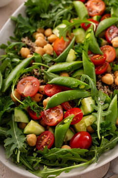 Fresh vegetables and quinoa salad with chickpeas, arugula and fresh peas with avocado ranch dressing