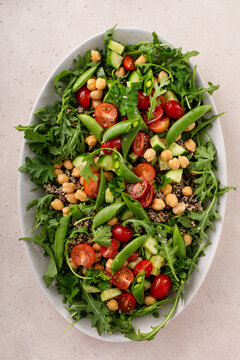 Fresh vegetables and quinoa salad with chickpeas, arugula and fresh peas with avocado ranch dressing