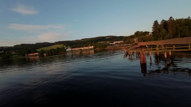 Low Angle FPV Drone GlidingOver Calm Lake Water Alongthe Shoreline