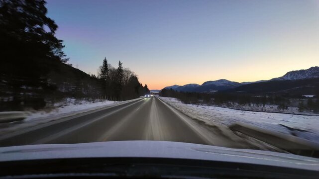 Dashboard camera view from a white car driving through the rural landscape near Eide Norway, at sunrise.