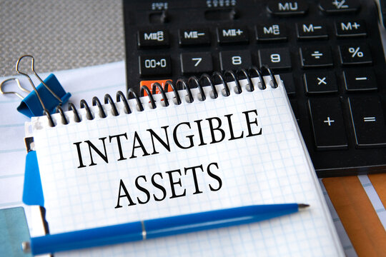 Notebook with the words INTANGIBLE ASSETS in the notebook on the background of a black calculator