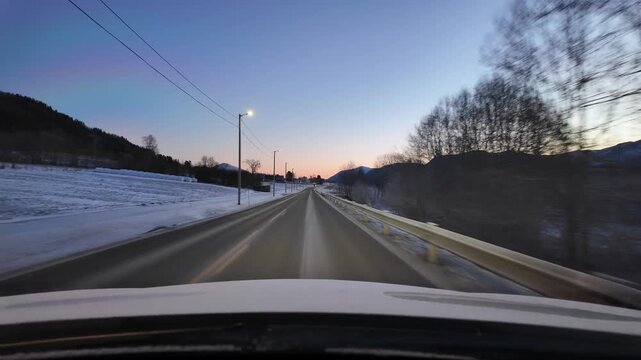 Dashboard camera view from a white car driving through the rural landscape near Eide Norway, at sunrise.