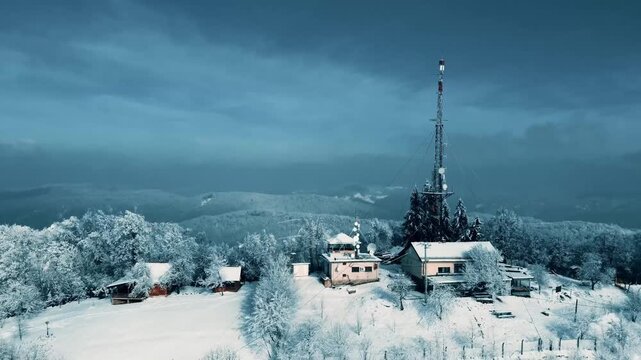 Aerial View of Snowy Mountain Peak with CommunicationTower and Cabins