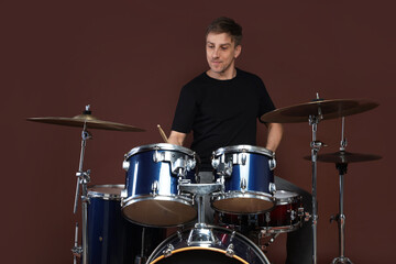 Obraz premium Man playing drums with drumsticks on brown background
