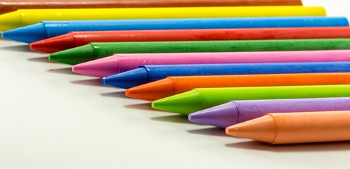 Fototapeta premium Colorful Wax Crayons Arranged in a Row on White Background