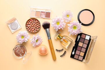 Fototapeta premium Spring composition with different makeup products and pink chrysanthemum flowers on beige background, flat lay