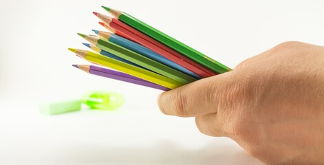 Naklejka premium Hand Holding Colorful Pencils with Sharpener on White