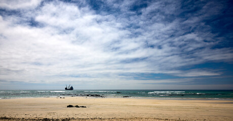 Bewölkter Sandstrand mit Küstenlinie: Weite Landschaftsaufnahme eines Strandes bei bedecktem Wetter. © Olgierd Kajak