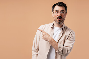 Fototapeta premium Surprised man with glasses pointing left, showing important information or advice