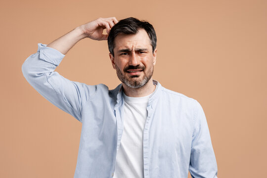 Confused man scratching head feeling puzzled, uncertain, having memory loss or doubt