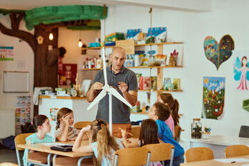 Teacher demonstrating a wind turbine model to engaged elementary students in a colorful classroom science lesson © .shock