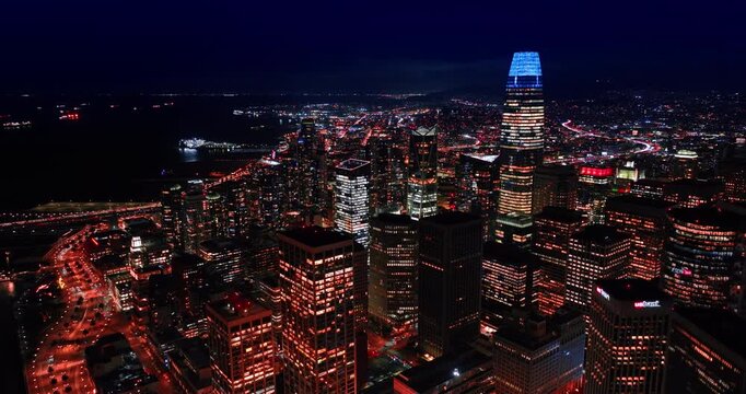 Fantastic illumination of San Francisco, California, USA at night. Approaching neon top of Salesforce tower from drone.