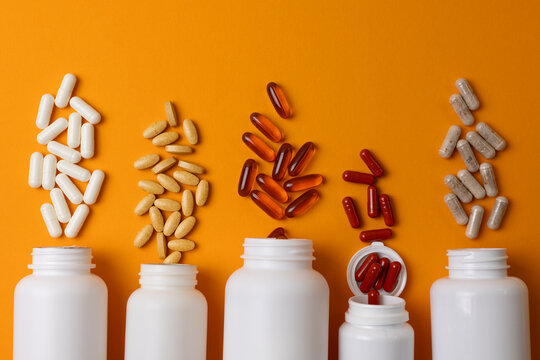 Vitamins On Neutral Background. Assorted Supplement Bottles With Capsules On Plain Backdrop