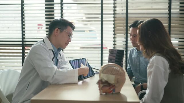 Professional neurologist explaining brain scan results during medical consultation with couple at clinic office focused discussion diagnostic imaging healthcare expertise patient care concept.	