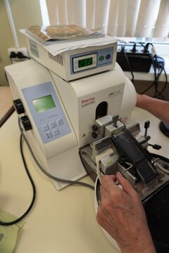 A technician adjusts a Thermo Scientific HM340E rotary microtome during tissue sectioning. The laboratory device cuts thin histology samples for microscope slides.  