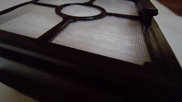 A detailed macro cinematic sequence showcasing the delicate and complex structure of a high-efficiency HEPA filter. The footage focuses on the woven white mesh designed to capture microscopic dust, po