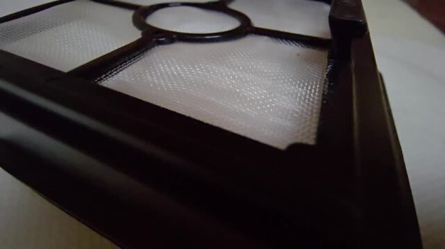 A detailed macro cinematic sequence showcasing the delicate and complex structure of a high-efficiency HEPA filter. The footage focuses on the woven white mesh designed to capture microscopic dust, po