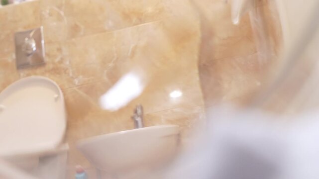 Black and tan dachshund in red clothing stands beside the open door of a front loading washing machine indoors, suggesting a playful household laundry routine with clothes inside