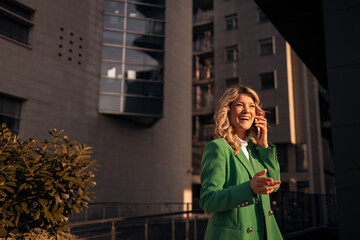 Fototapeta premium Successful woman talking on phone laughing urban setting