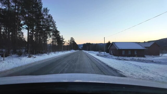 Dashboard camera view from a white car driving through a rural winter landscape at Angvika, near Kristiansund, Norway.