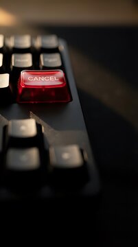 Red cancel button on black computer keyboard with dramatic lighting and shallow depth of field for business and technology concepts.