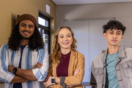 Diverse coworkers standing in office wearing smartwatches, beanie, tan blazer and denim jacket